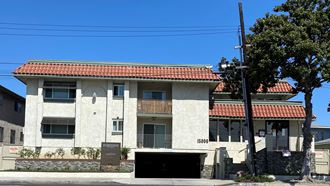 a white building with a red roof and a black garage door