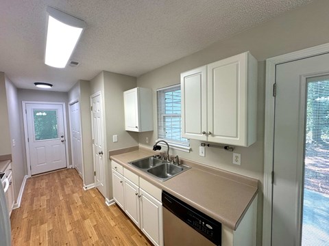 A kitchen with white cabinets and a wooden floor.