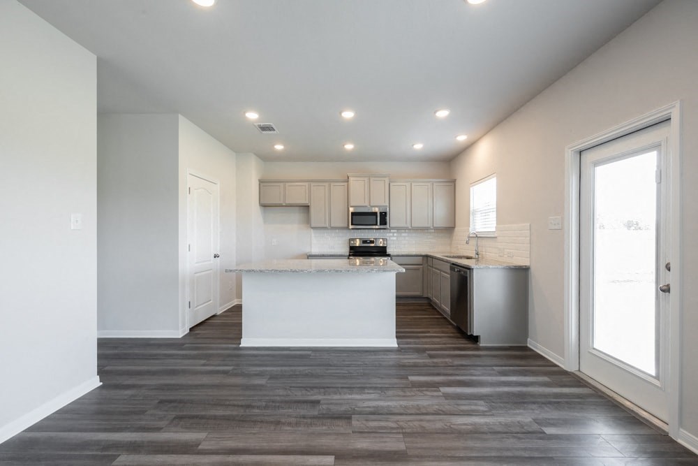 a white kitchen with a large window and a white counter top