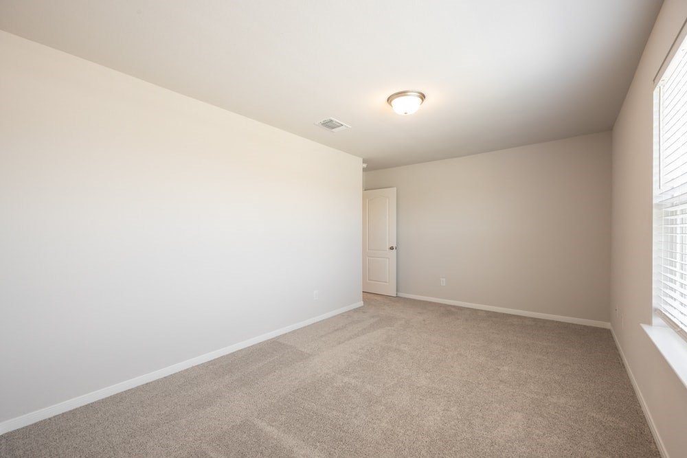 a spacious living room with a carpeted floor and a window