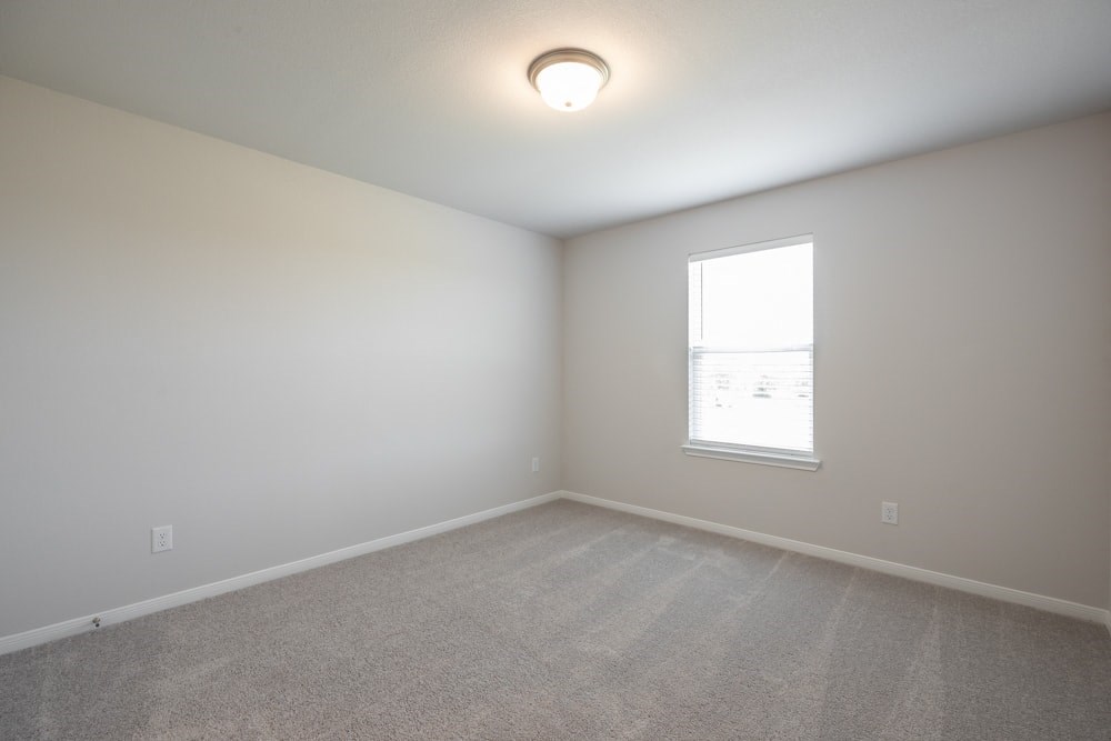 an empty room with a window and white walls