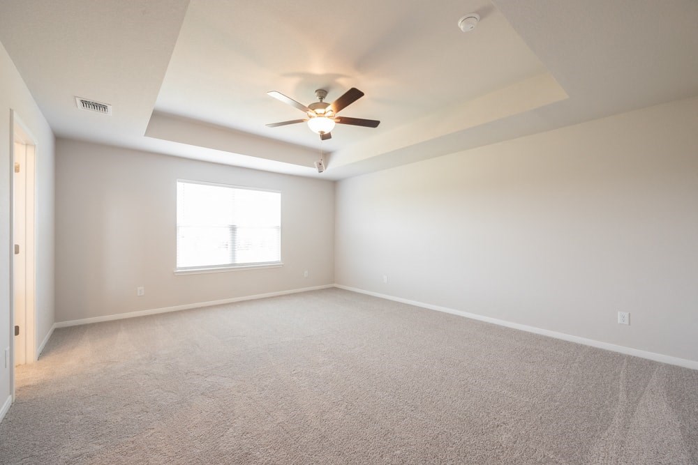 an empty living room with a ceiling fan and a window