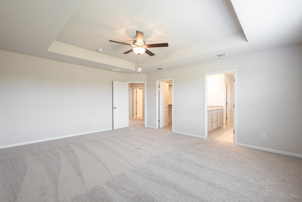 an empty living room with a ceiling fan and white walls