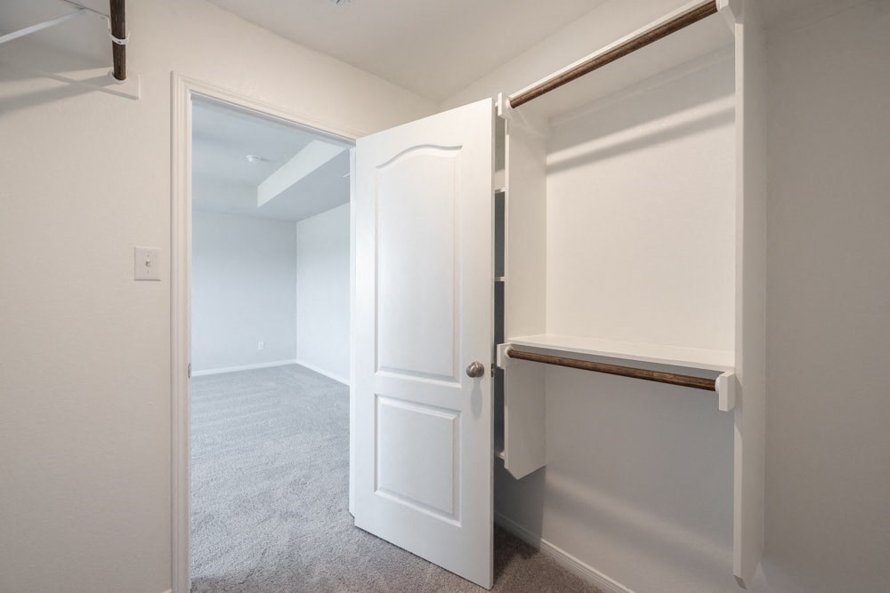 a small closet with a white door and a hallway to a bathroom