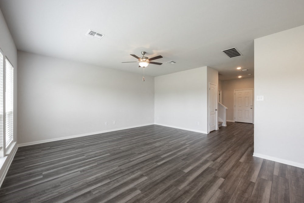 an empty living room with white walls and a ceiling fan