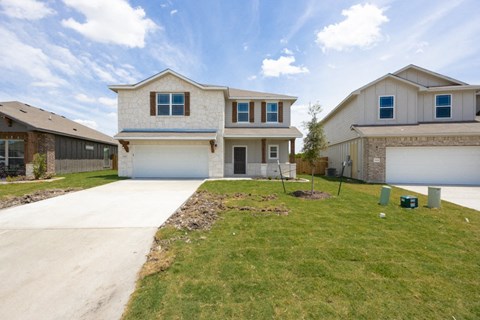 a beige house with a driveway and a lawn