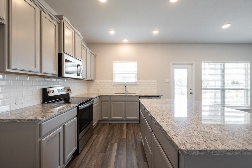 a kitchen with granite counter tops and white cabinets