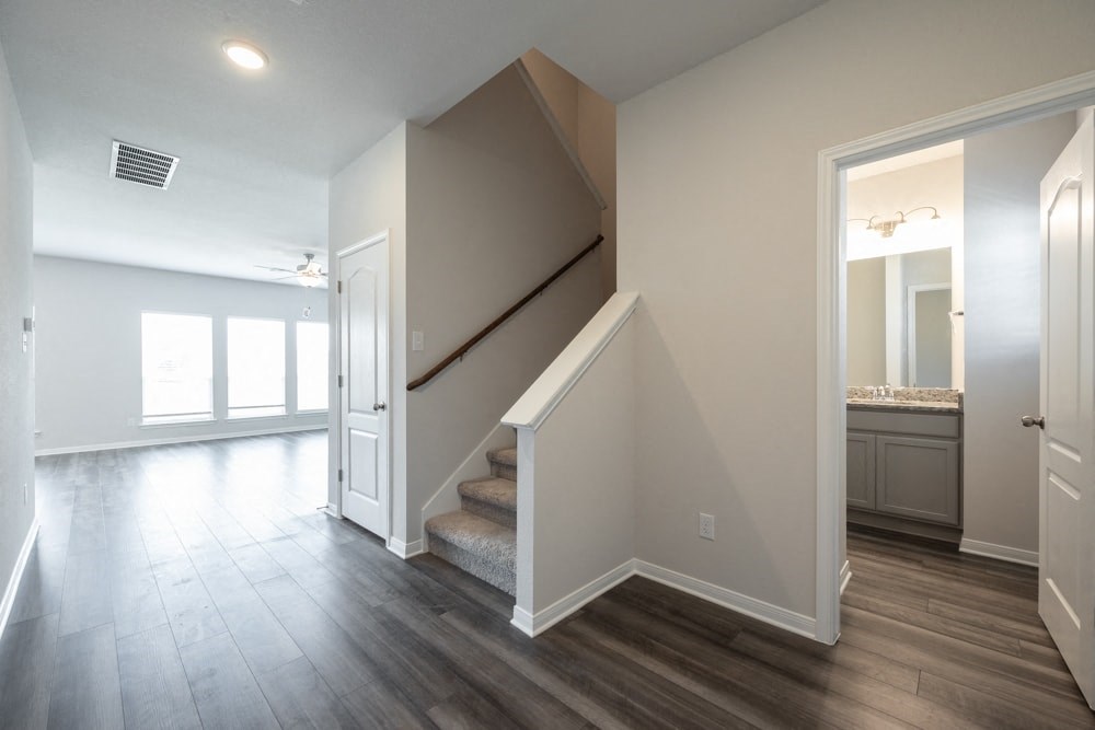 the landing of a staircase in a home with a hallway and a door to a