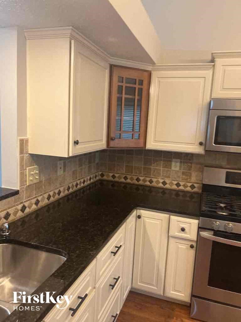 a kitchen with white cabinets and a black counter top