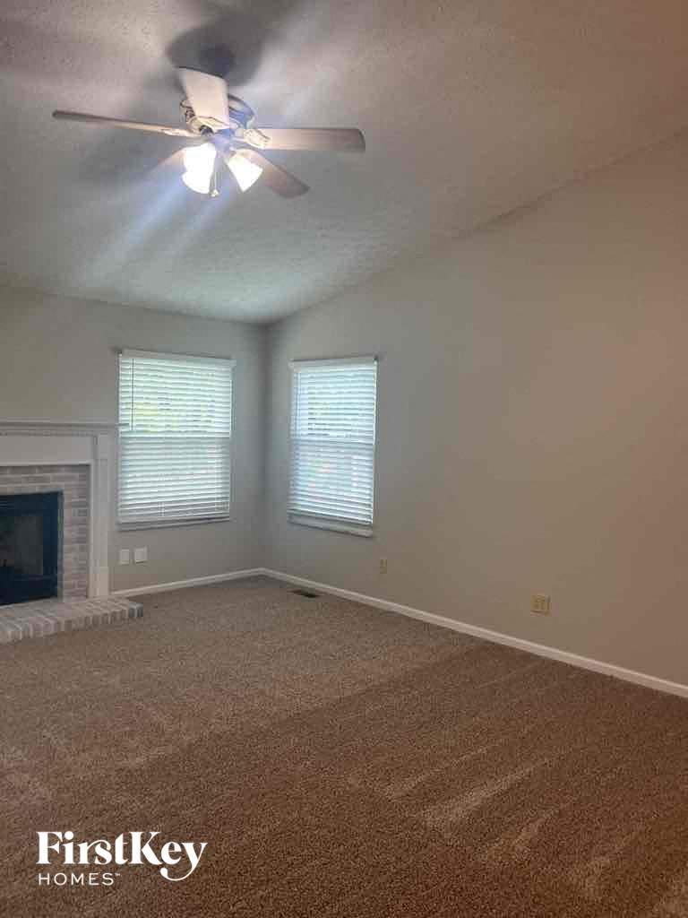 an empty living room with a ceiling fan and a fireplace