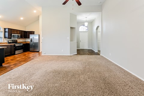 a living room with a rug and a kitchen with stainless steel appliances