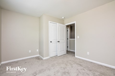 a bedroom with white doors and carpet and a closet