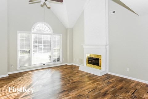 A spacious room with a fireplace and a ceiling fan.