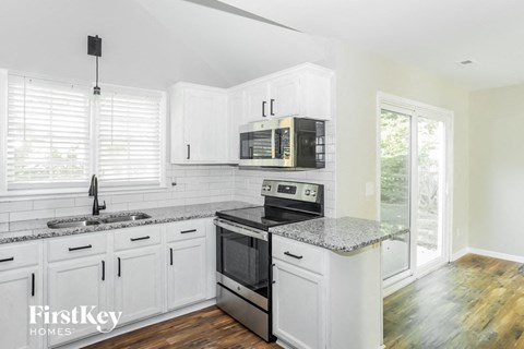 A kitchen with white cabinets and a granite countertop.