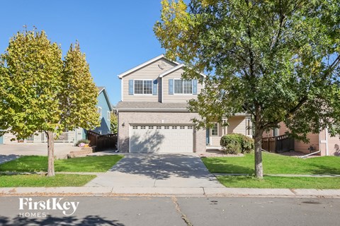 a house with a driveway and trees in front of it
