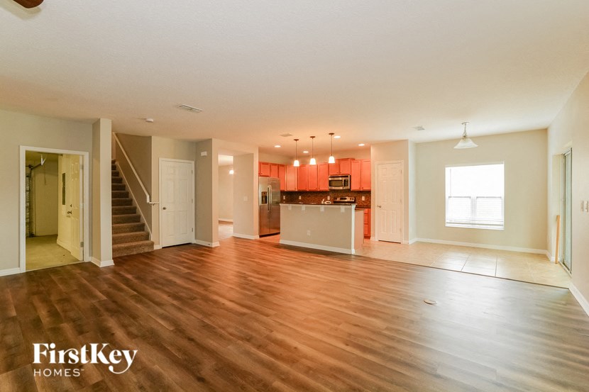an empty living room and kitchen with wood floors