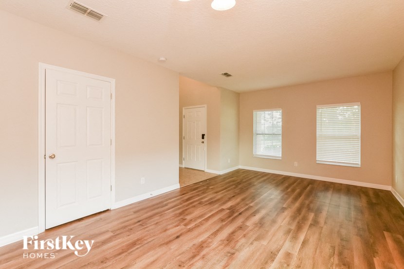 an empty living room with wood floors and a white door