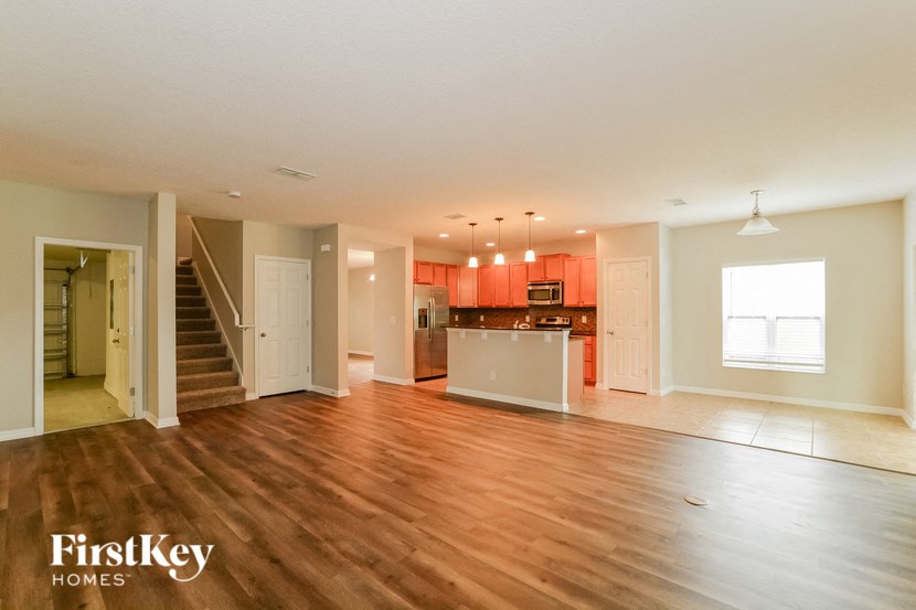 an empty living room and kitchen with wood floors
