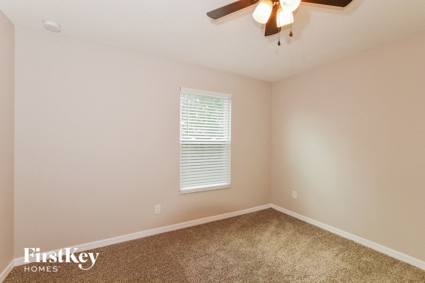an empty bedroom with a ceiling fan and a window