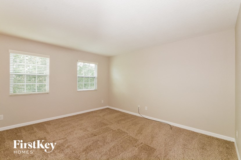 a bedroom with carpet and two windows
