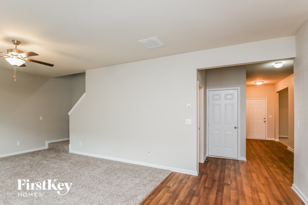 A room with a fan and a door leading to another room.