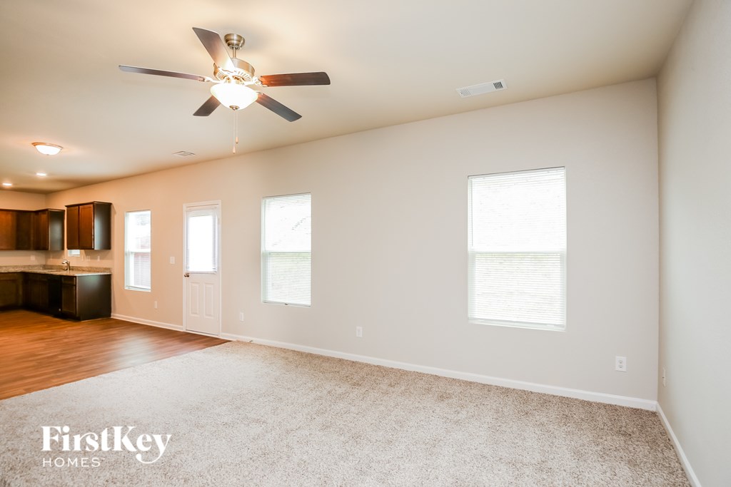 A spacious room with a ceiling fan and carpeted floor.