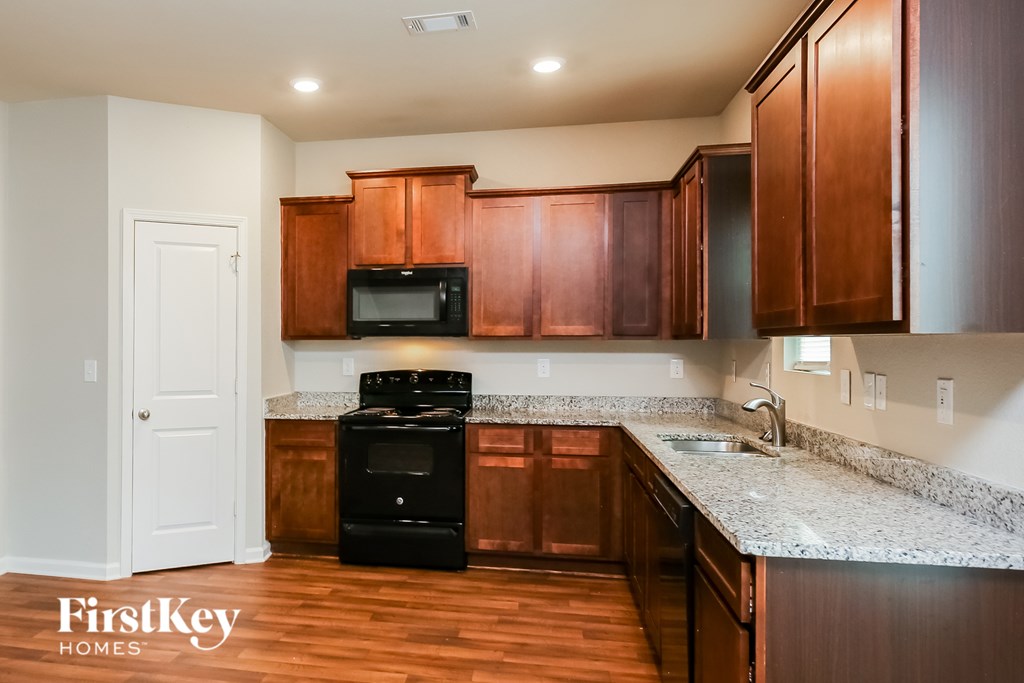 A kitchen with wooden cabinets and a black stove top oven.