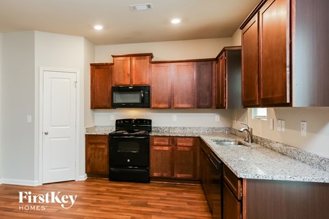 A kitchen with wooden cabinets and a black stove top oven.