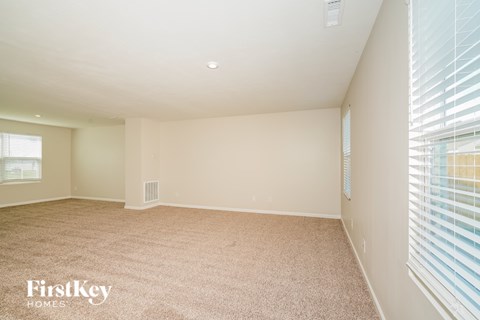 A spacious room with a carpeted floor and a window with blinds.