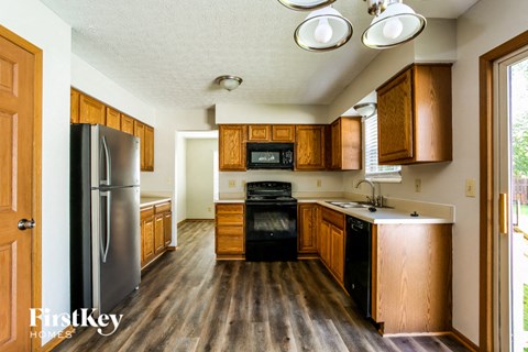 A kitchen with wooden cabinets and a black fridge.