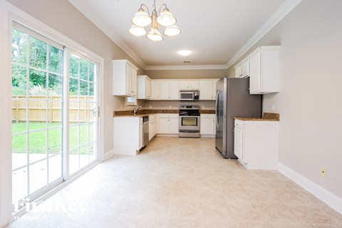 a large kitchen with white cabinets and a sliding glass door