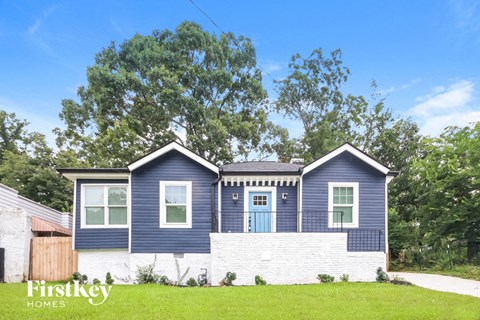 a blue and white house with a white brick fence and a tree