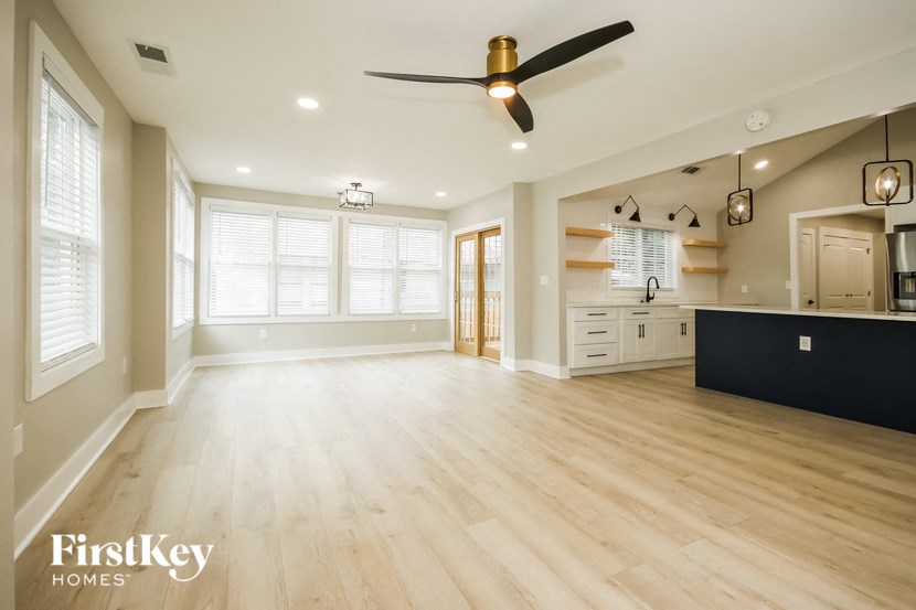 an open kitchen and living room with wood flooring and a ceiling fan