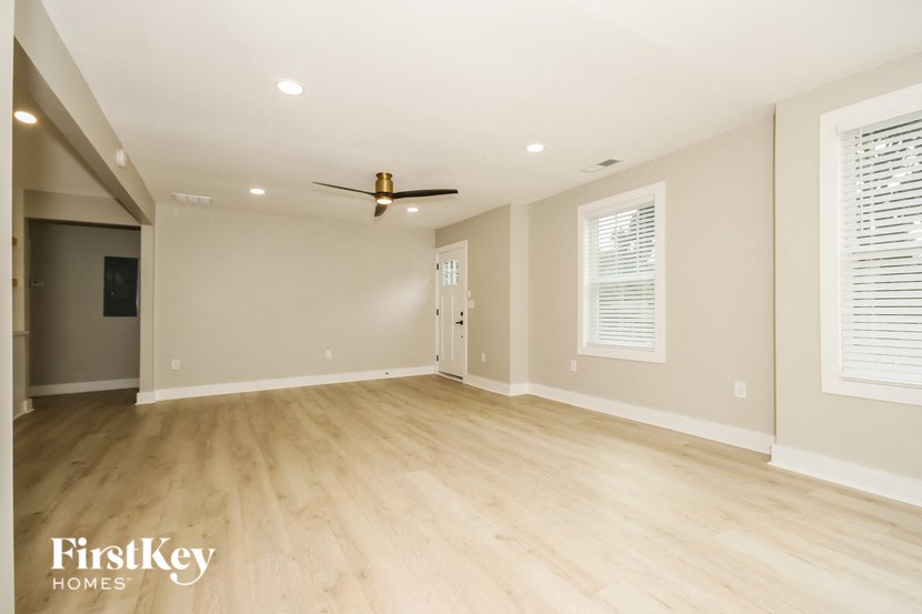 an empty living room with wood floors and a ceiling fan