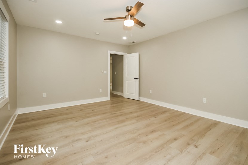 the spacious living room with hardwood floors and a ceiling fan