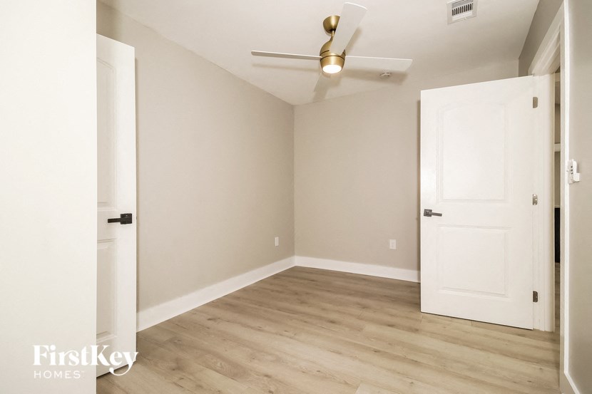 an empty room with a white door and a ceiling fan