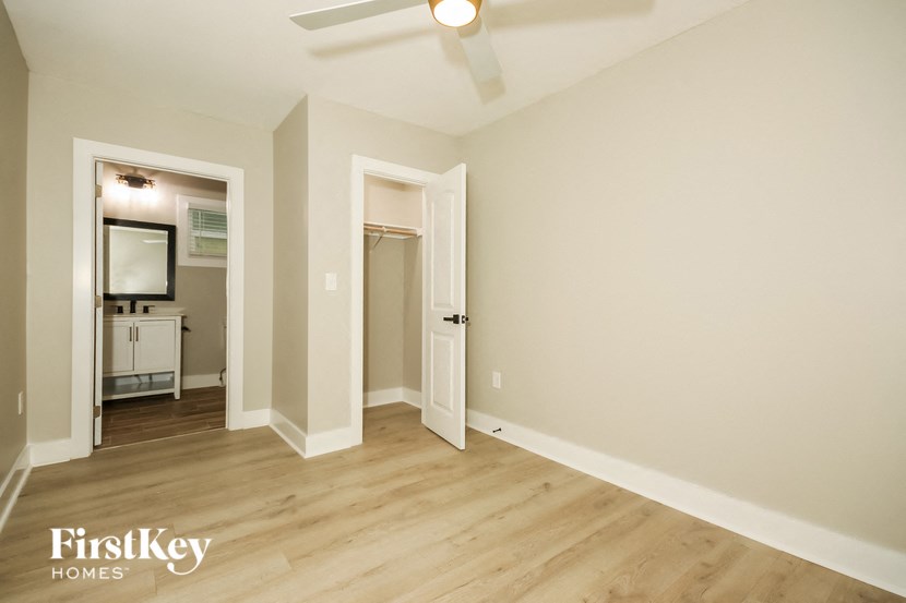 a living room with hardwood floors and white walls and a door to a bathroom