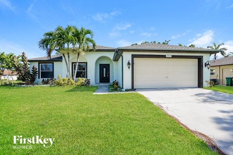 A house with a garage and a palm tree in front.