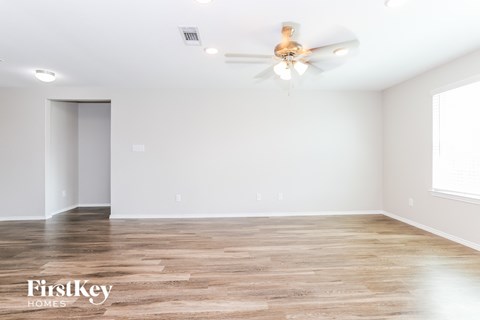 the spacious living room with wood flooring and a ceiling fan
