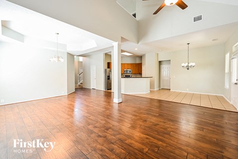 an empty living room with wood floors and a kitchen