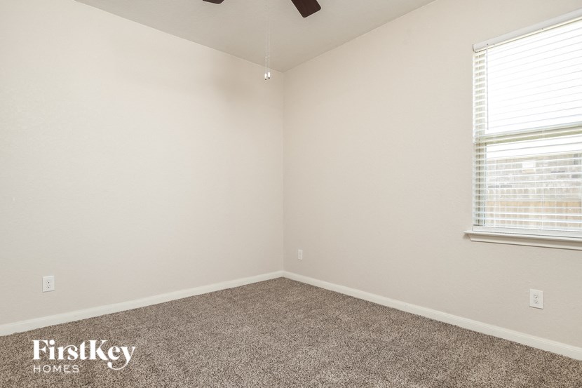 the bedroom of a small house with carpet and a window