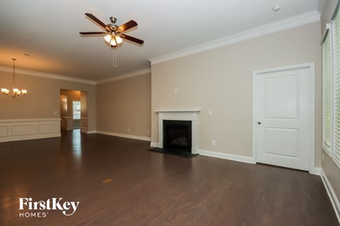 an empty living room with a fireplace and a ceiling fan