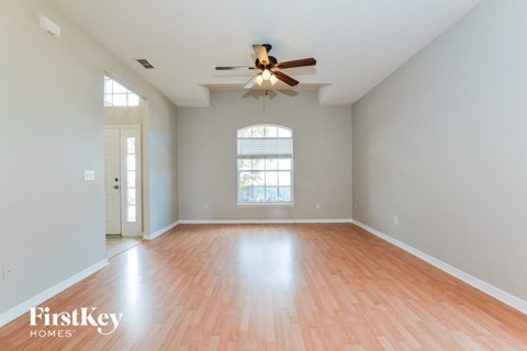 an empty living room with wood floors and a ceiling fan