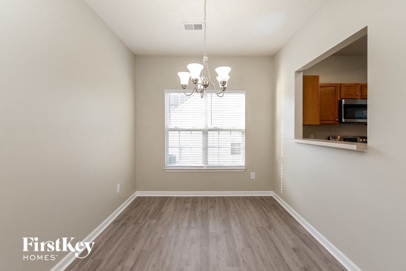 an empty dining room with a window and a chandelier