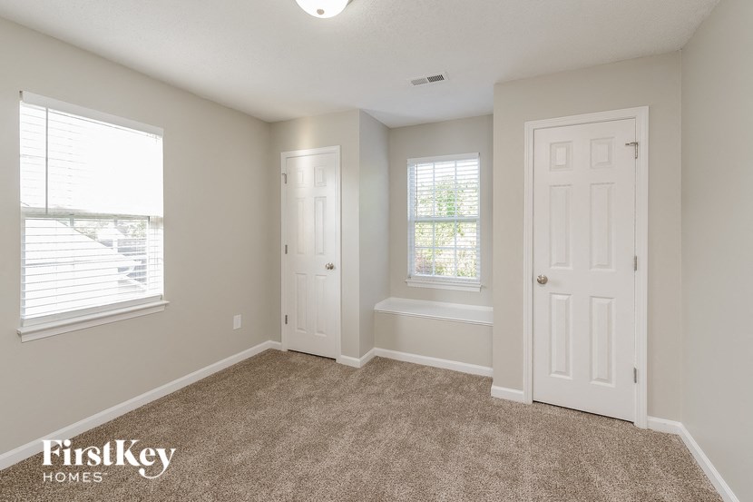 an empty living room with two windows and a white door