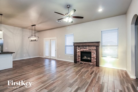 A spacious living room with a fireplace and a ceiling fan.