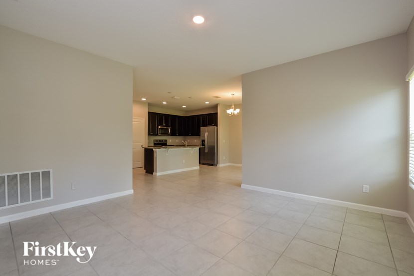 A spacious room with a white floor and walls, and a chandelier hanging from the ceiling.