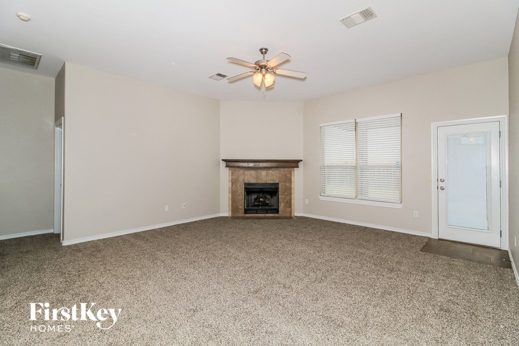 A spacious living room with a fireplace and a ceiling fan.