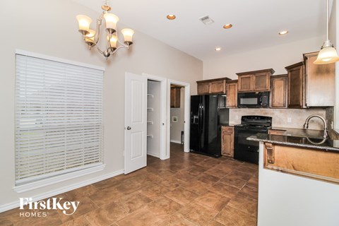 A kitchen with wooden cabinets and a black fridge.