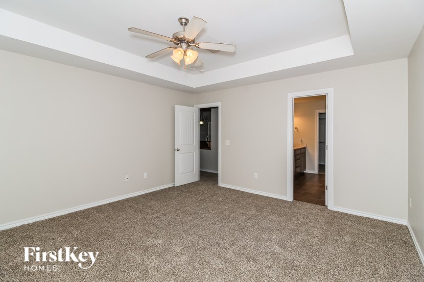 A spacious room with a ceiling fan and carpeted floor.